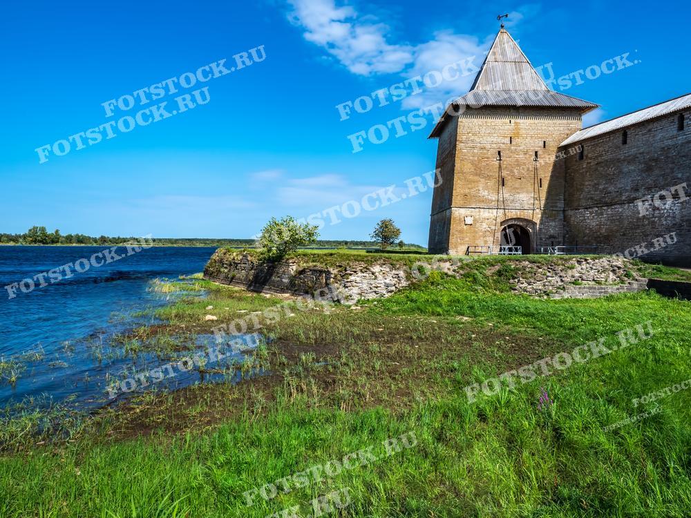 На фотографии изображена крепость Орешек, расположенная на берегу Ладожского озера в Шлиссельбурге, Ленинградская область. Фотография сделана в солнечный летний день. Она подходит для использования в туристических буклетах, исторических статьях и материалах о достопримечательностях Ленинградской области.